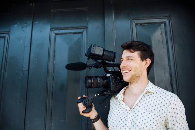 Smiling filmmaker with professional camera equipment